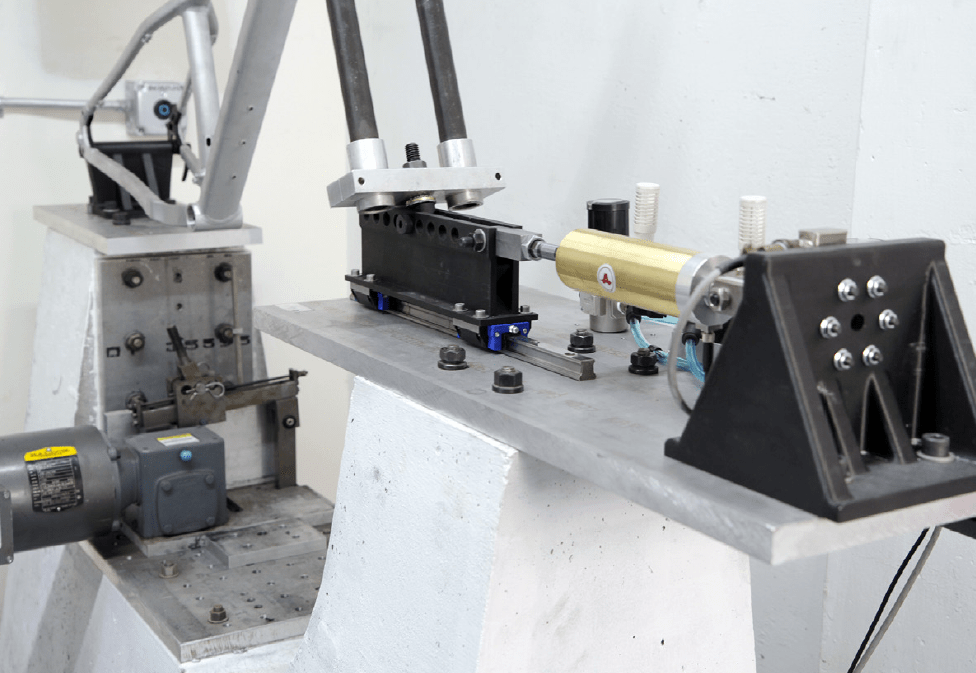 Black 3D printed Carbon Fiber-filled Nylon 12 holding fixtures anchor a bike frame during fatigue testing.